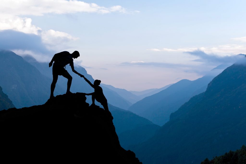Mann hilft Frau auf Berg Silhouette Berge